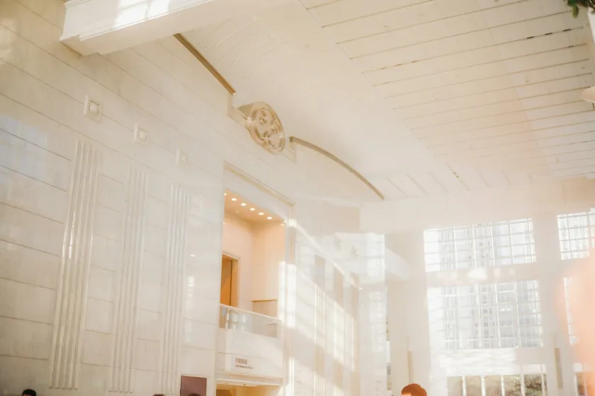 Hall d'hôtel baigné de soleil, avec de hautes fenêtres et un haut plafond blanc
