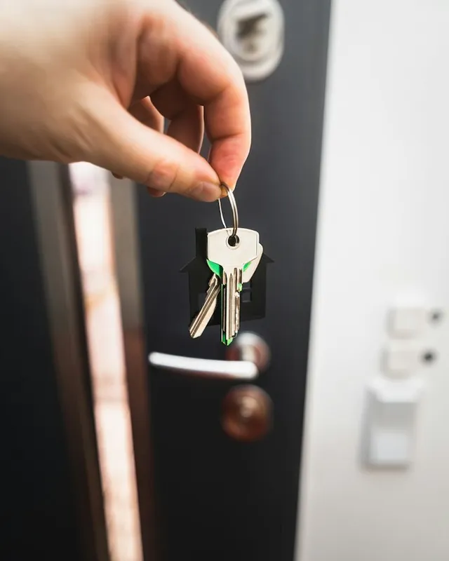 Main tenant un trousseau de clés près d'une porte d'entrée ouverte